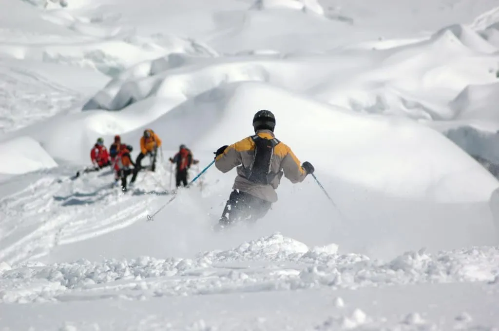 Ryhmä hiihtourheilijoita hiihtämässä Slovenian vuoristossa