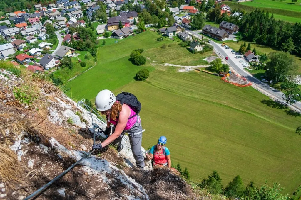 Mujer escalando la pared de roca en vía ferrata experiencia